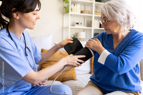Nurse measuring blood pressure of senior woman at home