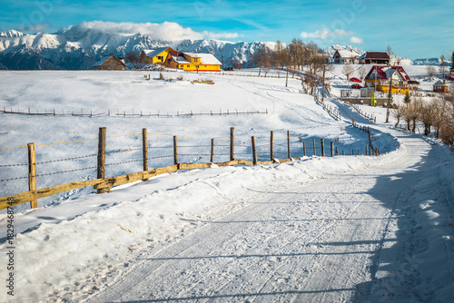 Snowy road and Pestera village with Bucegi mountains in background