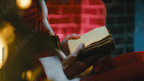 Santa Claus Reads a Book by the Christmas Fireplace