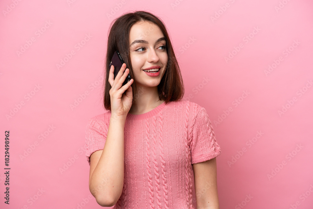 Fototapeta premium Young Ukrainian woman isolated on pink background keeping a conversation with the mobile phone with someone