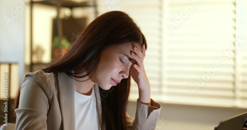Asian female office worker leaning forward with closed eyes, exhausted after long working hours, struggling to stay awake while facing job stress, concept of fatigue and burnout in modern workplace