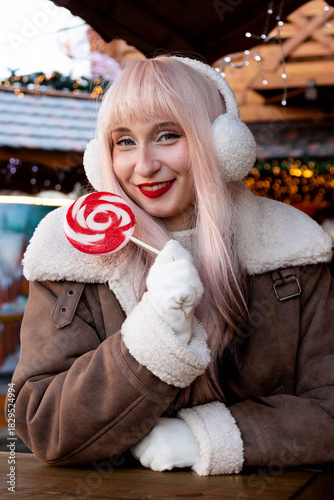 Beautiful girl with lollipop in her hands at Christmas market. Christmas mood. Christmas atmosphere
