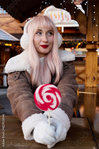 Woman in headphones at Christmas market. Winter Portrait with Lollipop
