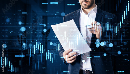 Businessman analyzing financial report with digital stock market chart overlays on dark background illustrating investment data and growth trends.