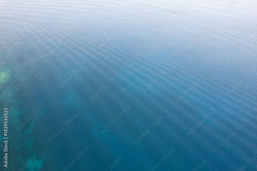Obraz premium Drone aerial of Tranquil blue water reflecting sunlight with gentle ripples in a peaceful setting