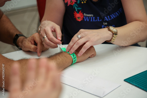 Professional putting a wristband on a patient's arm, a caring moment ensuring proper identification and safety in a modern medical setting, representing quality healthcare.