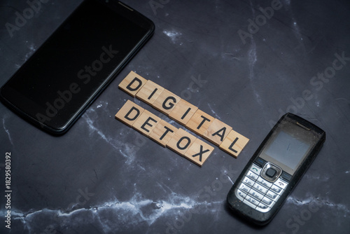 Flat lay composition featuring a Digital Detox sign surrounded by a smartphone, headphones, and laptop. Concept of unplugging, reducing screen time, and mental health awareness