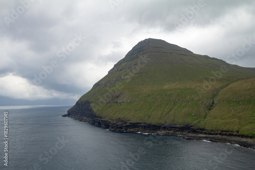 Steep green mountain rising over the Fjord of Gjógv, a classic Faroe Islands hiking viewpoint.