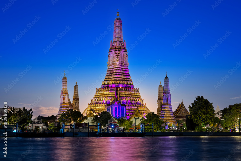 Fototapeta premium 26 November 2025 Beautiful Sunset colours of Thai Temple Wat Arun on Chao Phraya River in BKK Bangkok Thailand. The magic colourful neon light display on the temple at sunset is magical.