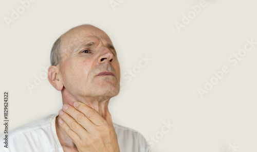 Bold senior man is holding his throat. Cold or thyroid gland health concept