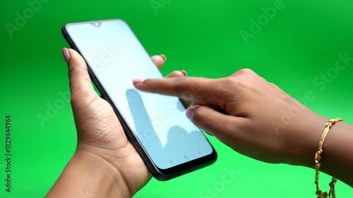 Close-up shot of a person's hand holding and touching a smartphone screen with a green background, 4K Footage
