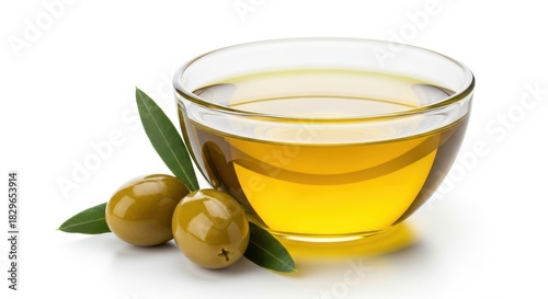Glass bowl of extra virgin olive oil with green olives and leaves
