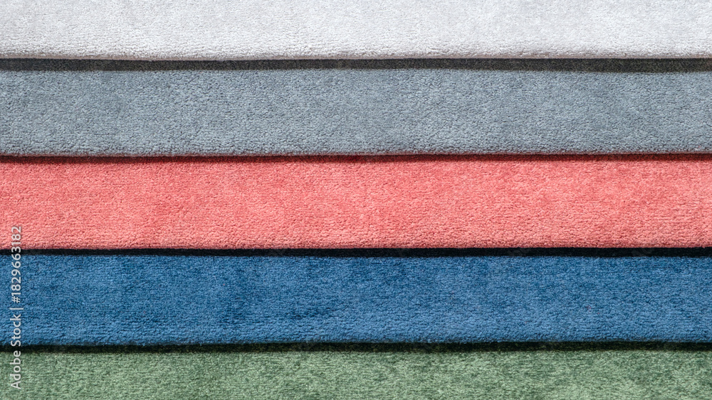 Fototapeta premium A row of different colored towels. The towels are blue, green, pink, and red. They are stacked on top of each other
