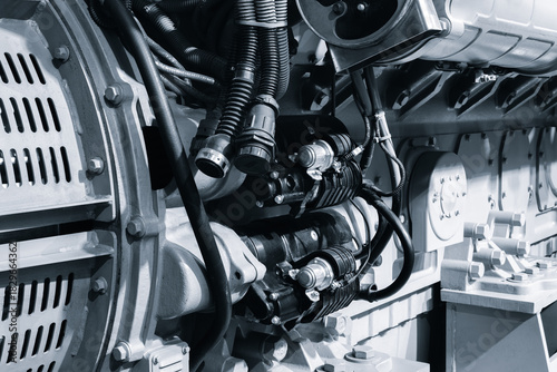 large blue diesel engine generator with  black hose attached to it. hose connected to engine and positioned in center. engine is powerful device, likely used for industrial purposes