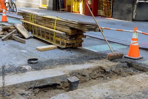 Road construction is taking place with tools materials set up along street for repair work.