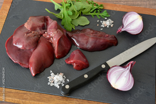 Raw Chicken Livers with Red Onions and Herbs on a Dark Cutting Board high angle
