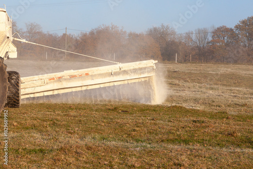 Close up on a chemical drop boom spreader spreading fertiliser on a farm pasture in winter, chemical fertilisation