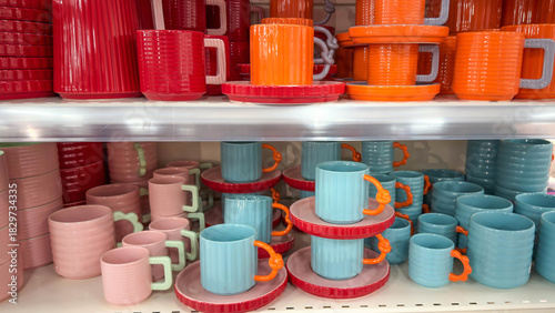 Colorful ceramic mugs and plates displayed on store shelves. Bright modern tableware in vibrant pastel tones, arranged neatly and ready for home decor or kitchenware shopping concepts.