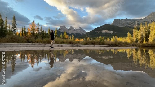 Woman Walking Near Lake with view of Three Sisters Mountains in Morning, Canmore, Canada