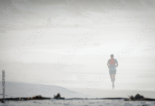 man running on the beach surrounded by fog or mist early morning concept sport, fitness, jogging, lifestyle with copy space