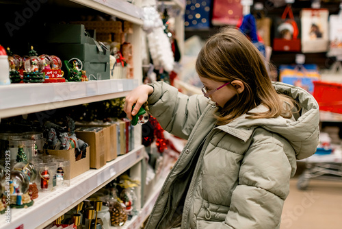 A girl in a store among Christmas decorations. Preparing for the New Year and Christmas. Buying decorations and gifts.