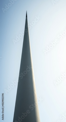A minimalist view of an extremely narrow, elongated pillar rising vertically against a bright sky, emphasizing its striking thinness and height ,isolated ,bright ,structure