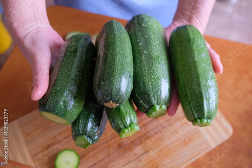 A woman and a man fry zucchini in a frying pan in an apartment in a darkened evening, preparing a raw product.