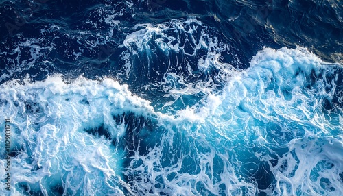 Fototapeta Naklejka Na Ścianę i Meble -  Aerial ocean view featuring a foamy white wave cresting against dark blue depths of the water