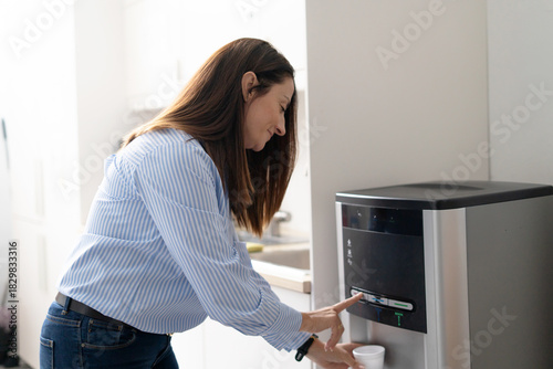 Woman filling water cup at office cooler