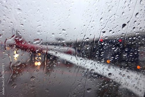Blurred window view to air field with aircraft silhouettes through wet glass in the overcast weather in the evening