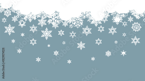 A winter scene with white snowflakes falling from a snow covered top against a light blue background