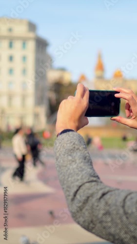 Woman taking an outdoor media content of barcelona iconic architecture on a city trip, capturing travel moments with a modern mobile phone