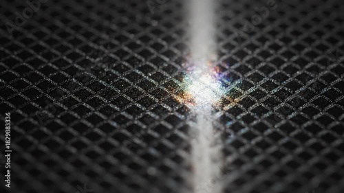 Light beam striking textured grid, creating a vibrant colorful spectrum. Refraction and energy concept.