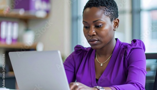 a black business woman with short hair wearing a purple blouse shirt focusing intensely on her documents in the office