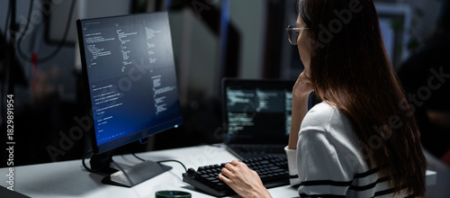 Cuadro en lienzo Rear view of a young programmer intensely reviewing code displayed on a monitor in a dark office