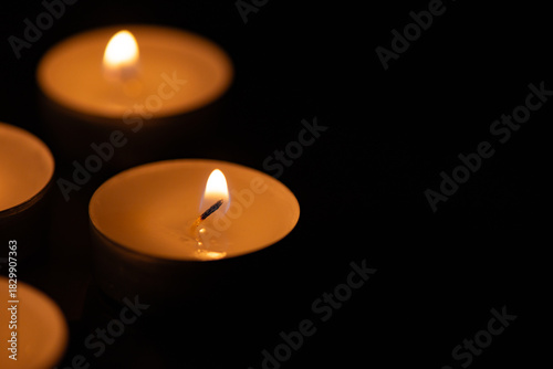 Glowing tealight candles against a dark background. Remembrance and Memorial Day Symbol. Perfect for themes of remembrance, meditation, spirituality, mourning, tranquility, or holiday celebrations.