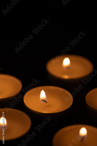 Glowing tealight candles against a dark background. Remembrance and Memorial Day Symbol. Perfect for themes of remembrance, meditation, spirituality, mourning, tranquility, or holiday celebrations.
