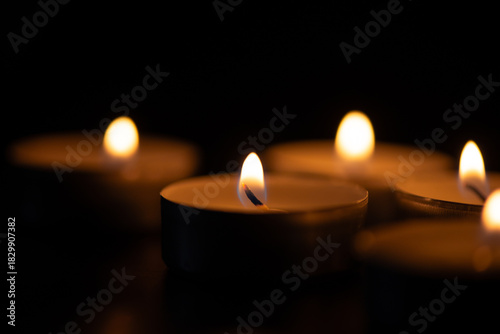 Glowing tealight candles against a dark background. Remembrance and Memorial Day Symbol. Perfect for themes of remembrance, meditation, spirituality, mourning, tranquility, or holiday celebrations.
