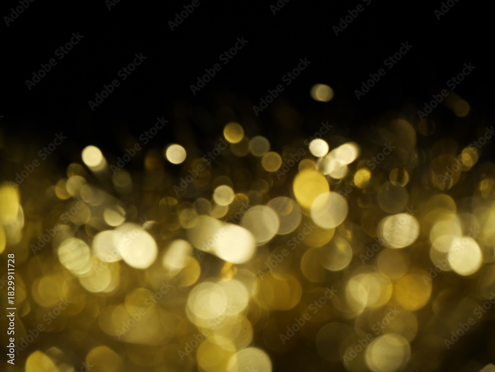 Obraz premium Golden festive bokeh glow. Festive background made of sparkling tinsel with bokeh effect. Great for Christmas, New Year, and celebration themes.