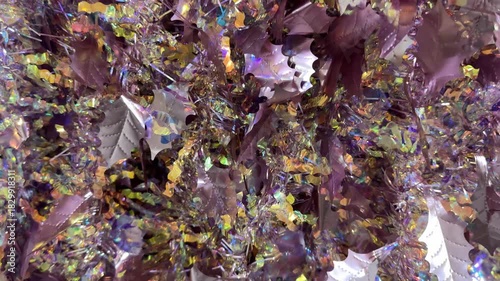 Close up background texture of christmas tinsels garland in holographic pink colors. Made of glossy materials, tinsels are used to decorate christmas tree or rooms in festivity. Merry Christmas