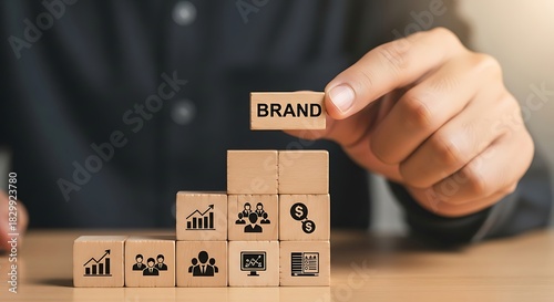 Businessman holding a wooden block with the word brand on top of a growth chart made of blocks, symbolizing brand building and success