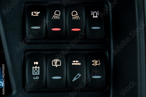 Detailed view of construction equipment switch panel featuring headlight controls, hydraulic function selectors and operational system buttons designed for industrial vehicle operation