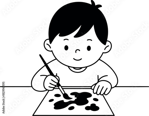 Young boy happily painting with a brush on paper