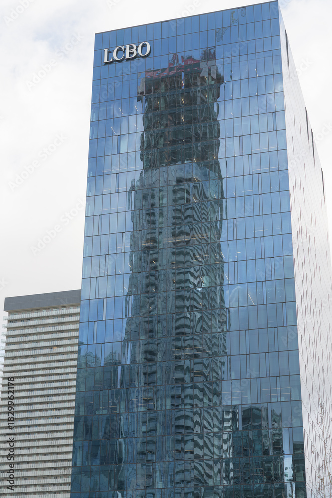 Fototapeta premium reflection of SkyTower at Pinnacle condominium complex on a modern office building with LCBO sign, 100 Queens Quay E, Toronto
