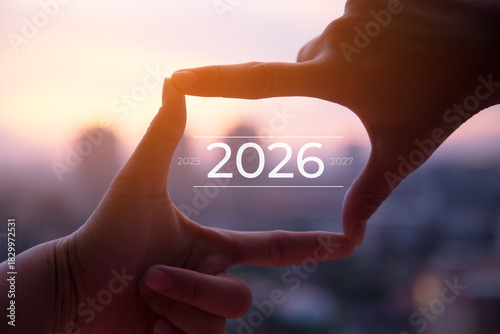 2026 new year celebration concept.Silhouette of Photo sign made by human hands on blurred sunset sky as background