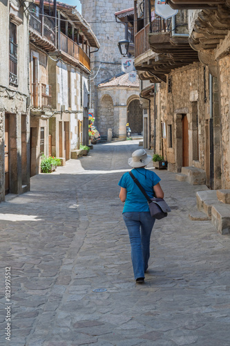 Female tourist seen from behind photographing the streets of the villages of the Sierra de Francia (Salamanca, Spain) in summer