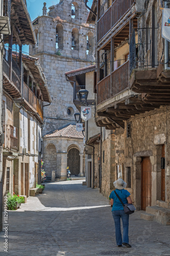 Female tourist seen from behind photographing the streets of the villages of the Sierra de Francia (Salamanca, Spain) in summer
