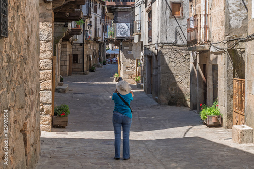 Female tourist seen from behind photographing the streets of the villages of the Sierra de Francia (Salamanca, Spain) in summer