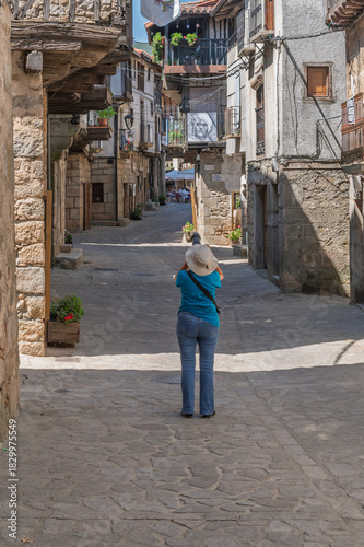 Female tourist seen from behind photographing the streets of the villages of the Sierra de Francia (Salamanca, Spain) in summer