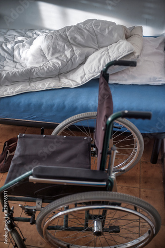 Empty wheelchair beside unmade bed in a healthcare room